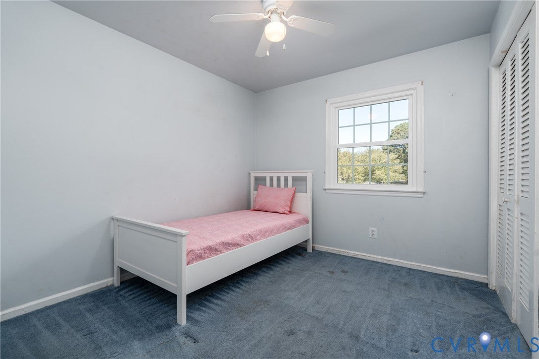9329 Totopotomoy Trail, Ashland, VA 23005 Room featuring wall-to-wall carpeting, a multi-pane window with trim, a white ceiling fan with integrated lighting, and a closet with louvered doors
