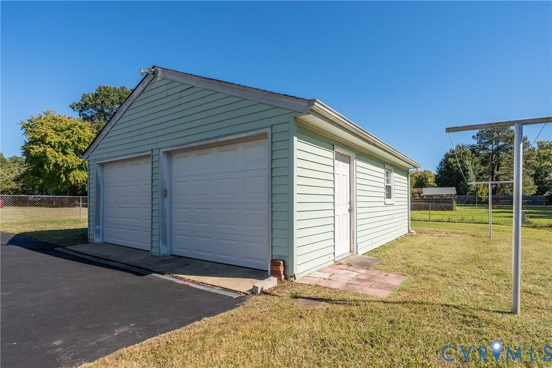 9329 Totopotomoy Trail, Ashland, VA 23005 Detached two-car garage featuring light green horizontal siding, two white roll-up doors, and an asphalt driveway
