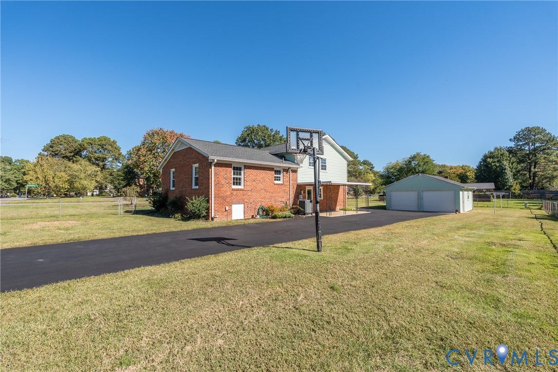 9329 Totopotomoy Trail, Ashland, VA 23005 Exterior featuring a brick and siding facade, detached two-car garage, expansive lot, and paved driveway