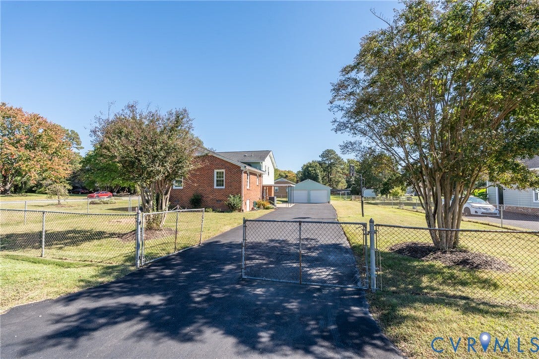 9329 Totopotomoy Trail, Ashland, VA 23005 Brick exterior, asphalt driveway, detached two-car garage, and chain-link perimeter fencing