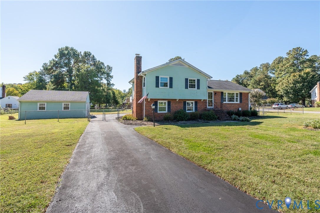 9329 Totopotomoy Trail, Ashland, VA 23005 Two-story residence featuring a brick and siding exterior, external brick chimney, asphalt driveway, and detached garage