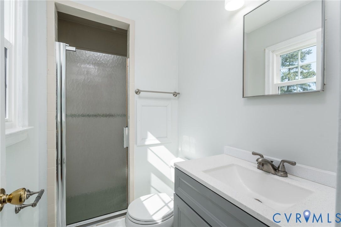 9329 Totopotomoy Trail, Ashland, VA 23005 Bathroom featuring a gray vanity with a stone-composite countertop, integrated sink, chrome-finish faucet, and a shower enclosure with textured glass