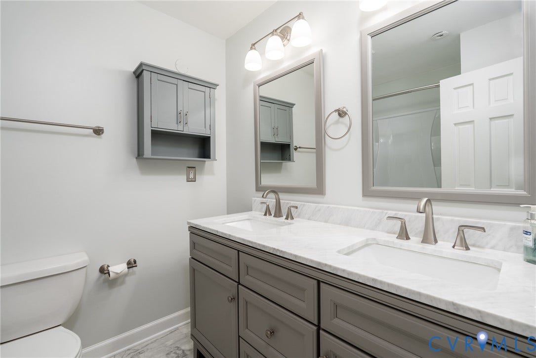 9329 Totopotomoy Trail, Ashland, VA 23005 Double vanity featuring a light-toned countertop, under-mount sinks, brushed nickel faucets, grey cabinetry, and framed mirrors