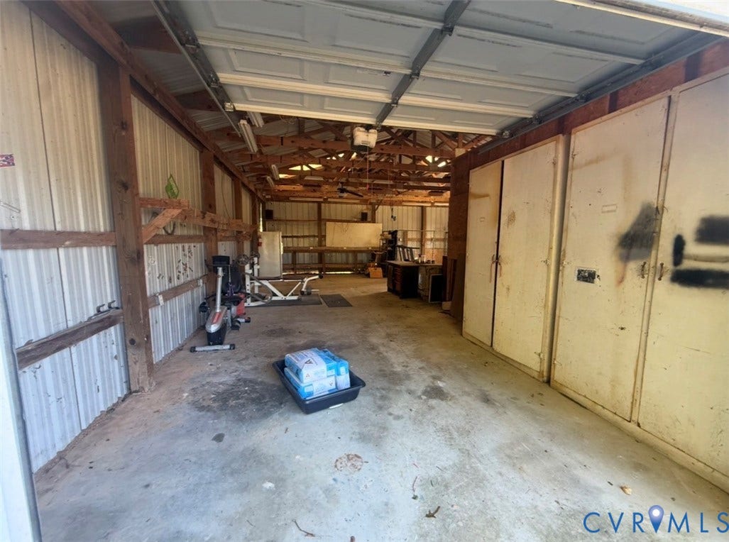 26691 Bell Road, Amelia, VA 23002 Expansive detached garage featuring corrugated metal wall cladding, exposed timber framing, concrete flooring, and built-in floor-to-ceiling storage cabinetry