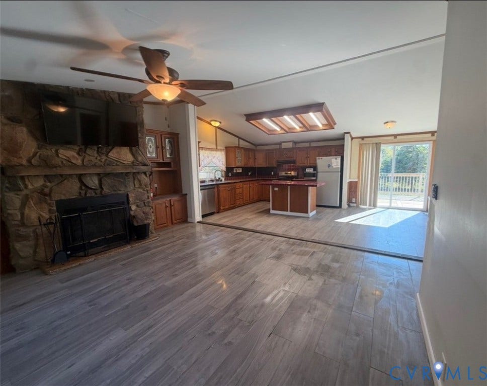 26691 Bell Road, Amelia, VA 23002 Stone-faced fireplace with hearth, wood-finish flooring, kitchen island, built-in cabinetry, and sliding glass doors