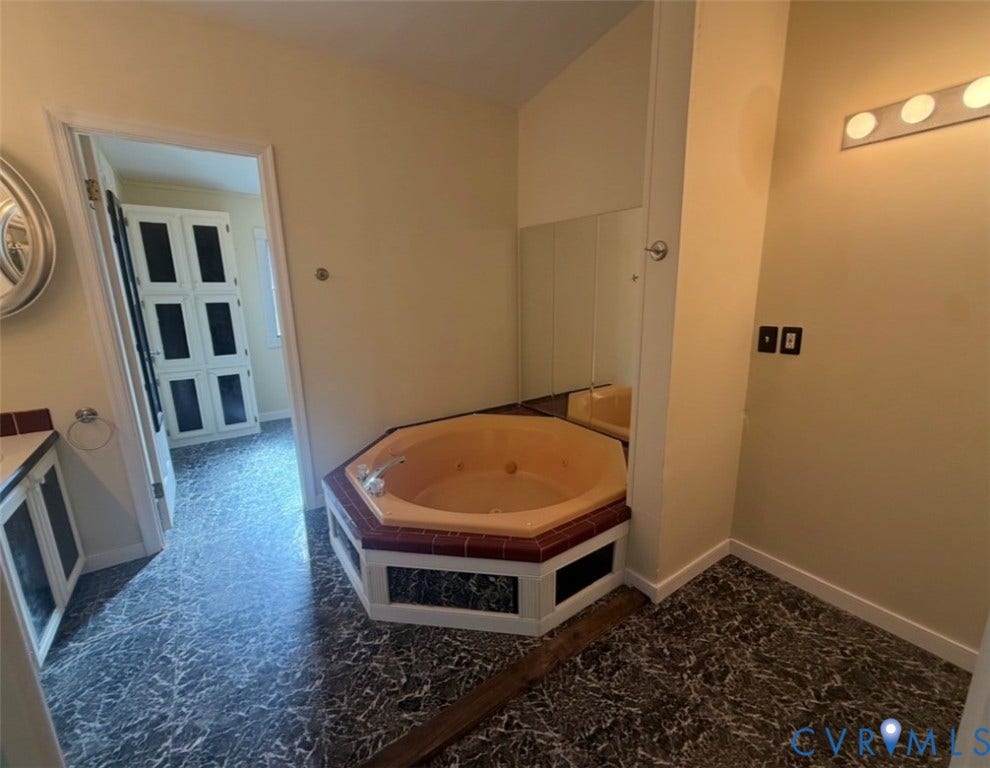 26691 Bell Road, Amelia, VA 23002 Octagonal soaking tub with tile surround, patterned flooring, wall-mounted mirror, and overhead vanity lighting