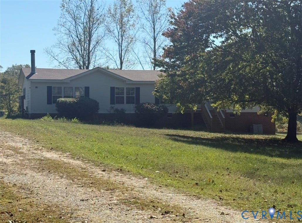 26691 Bell Road, Amelia, VA 23002 Single-story residence featuring light-colored horizontal siding, a chimney, wooden deck, and brick foundation masonry set on a lot with mature trees