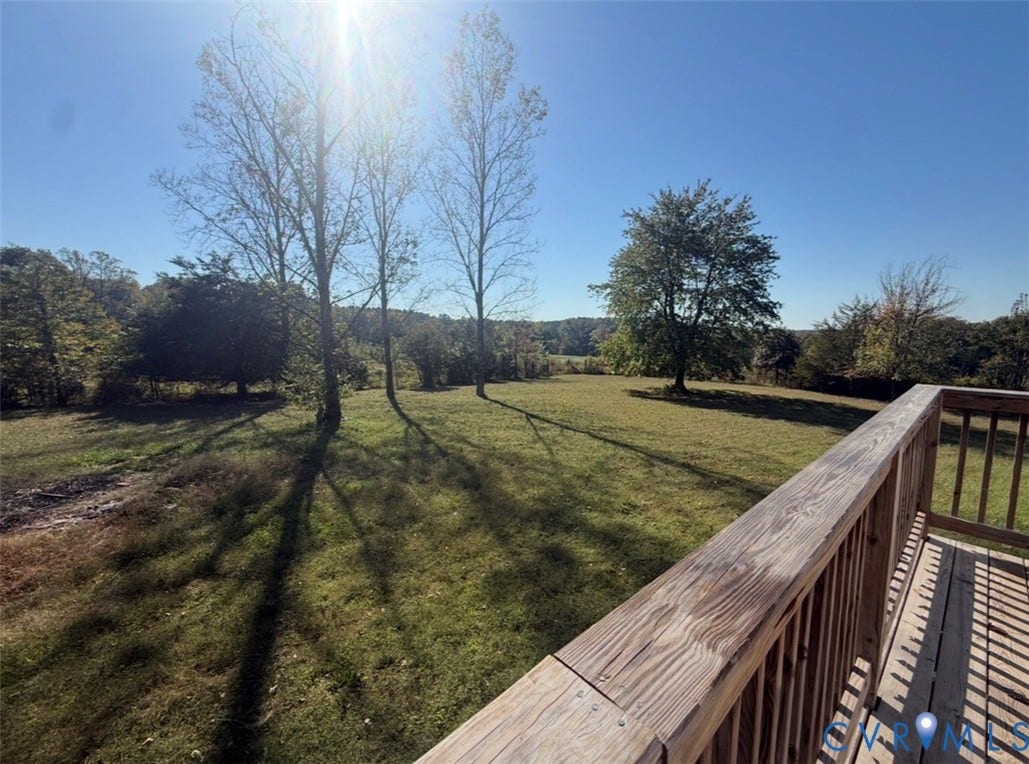 26691 Bell Road, Amelia, VA 23002 Elevated wooden deck featuring vertical balusters overlooking an expansive lawn with mature trees and native landscape