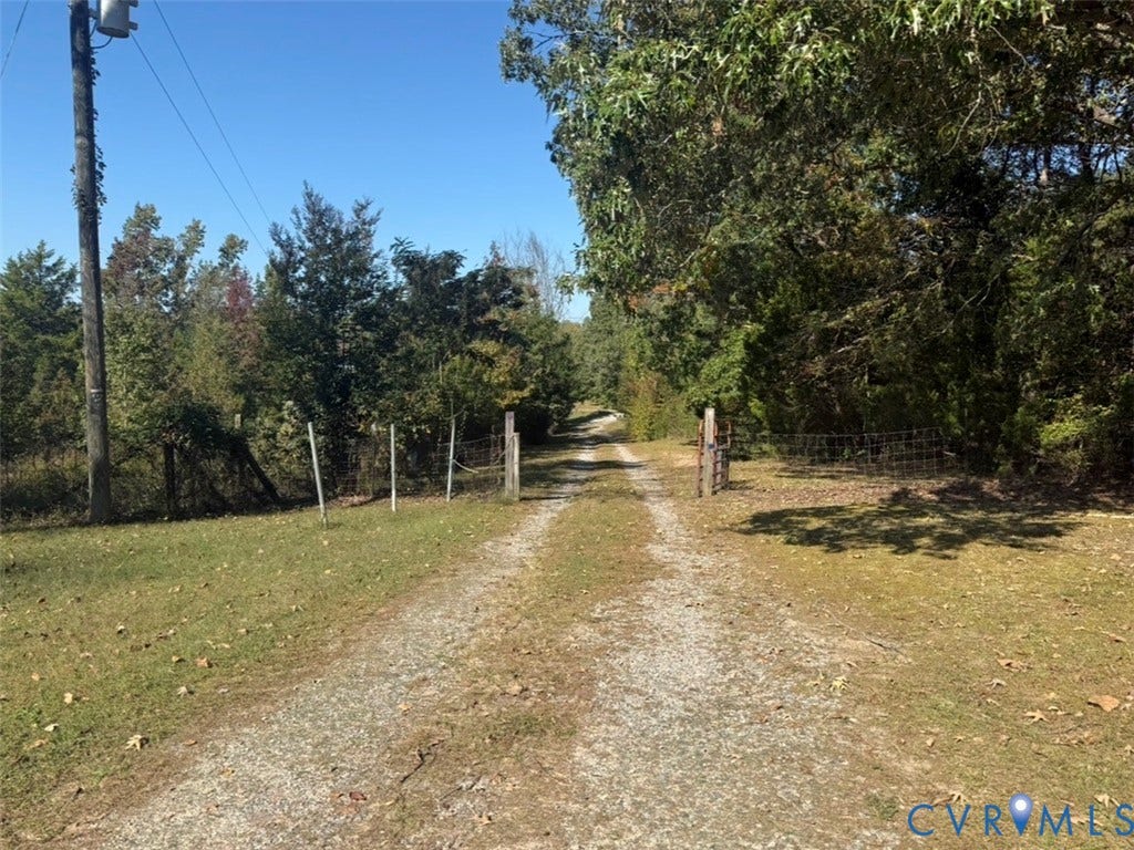 26691 Bell Road, Amelia, VA 23002 Gravel driveway flanked by perimeter wire fencing, wooden gate posts, and mature tree lines