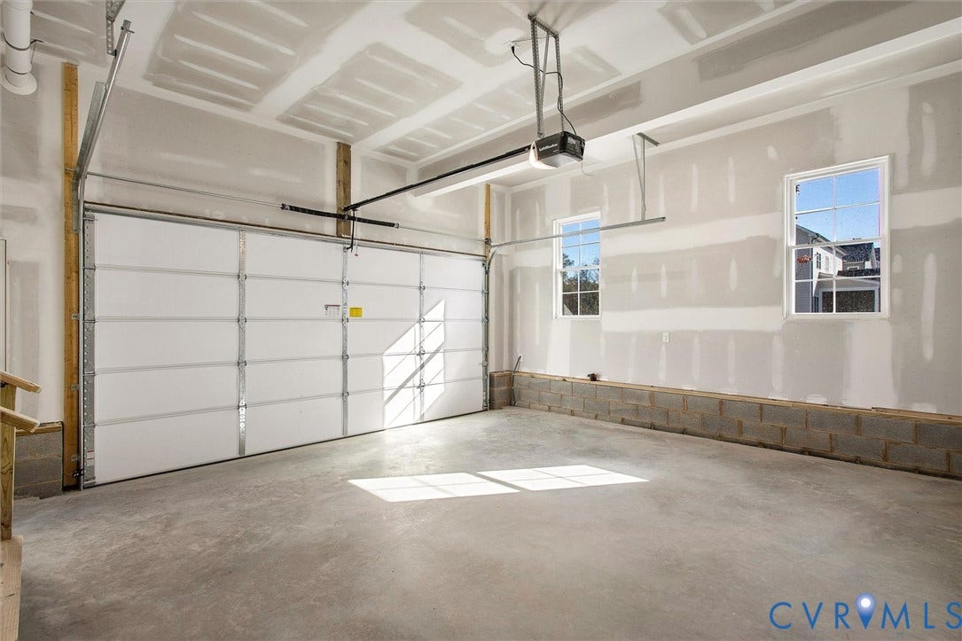 2851 Old Pump Road, Preserve At John Rolfe, Henrico, VA 23233 Spacious garage featuring a concrete floor, finished drywall, two windows, and an automated overhead door system