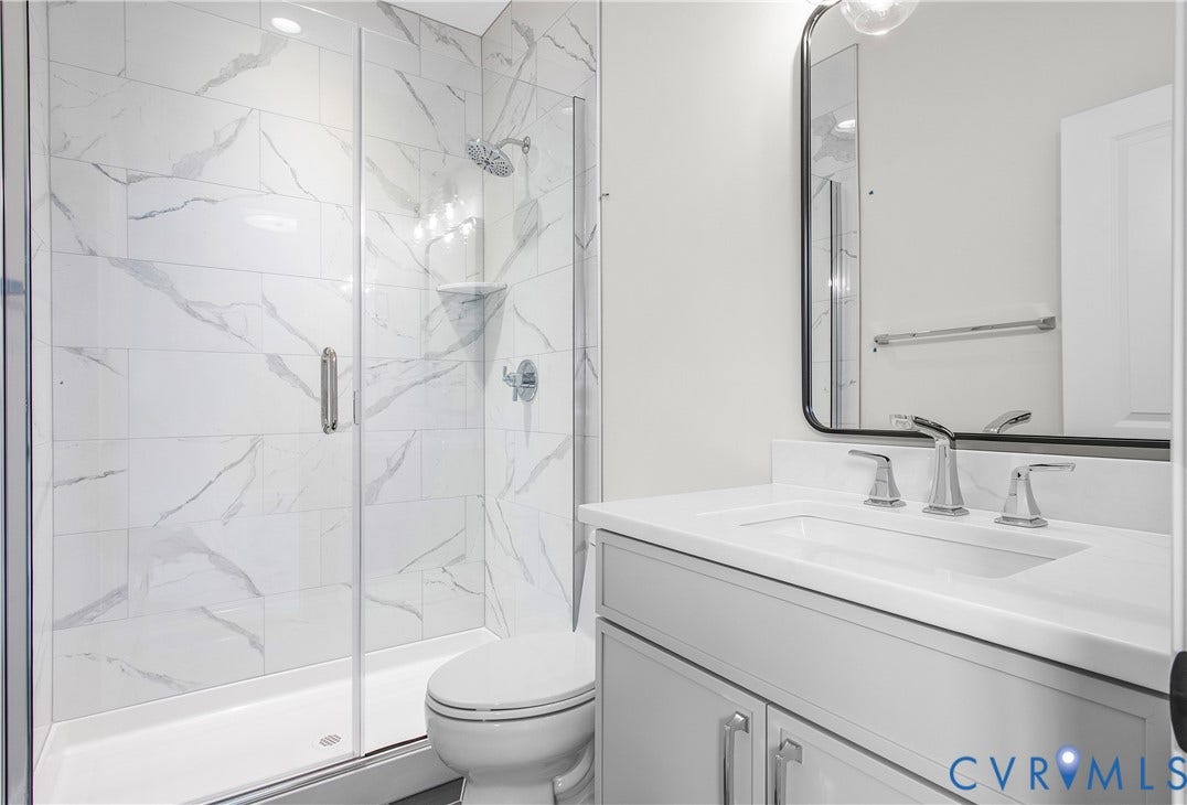 2851 Old Pump Road, Preserve At John Rolfe, Henrico, VA 23233 Bathroom featuring a walk-in shower with floor-to-ceiling veined tile surrounds, a glass enclosure, a white vanity with a composite countertop, and a framed mirror