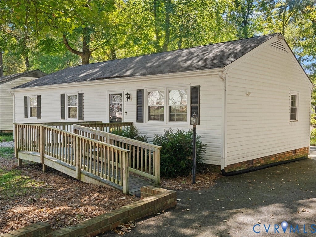 8708 Rainwater Road, Huntingcreek Hills, North Chesterfield, VA 23237 White vinyl siding exterior featuring a gable roof, wood-finish ramp, asphalt driveway, and brick garden edging