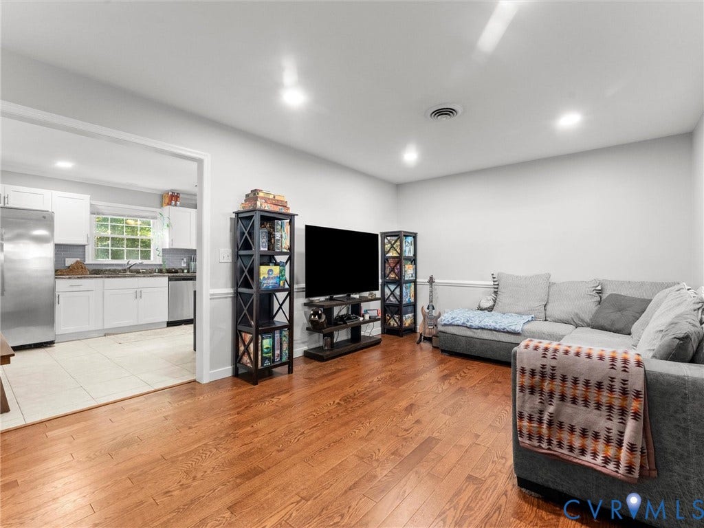 8708 Rainwater Road, Huntingcreek Hills, North Chesterfield, VA 23237 Interior space featuring wood-finish flooring, recessed lighting, and chair rail molding, with a kitchen area showcasing white cabinetry and stainless steel appliances