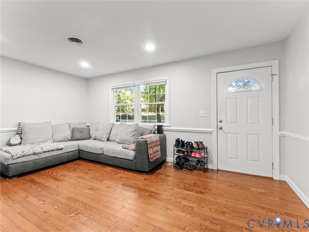 8708 Rainwater Road, Huntingcreek Hills, North Chesterfield, VA 23237 Hardwood flooring, neutral wall paint, white trim with chair rail molding, dual-pane windows, and a white six-panel exterior door with a semi-circular transom window