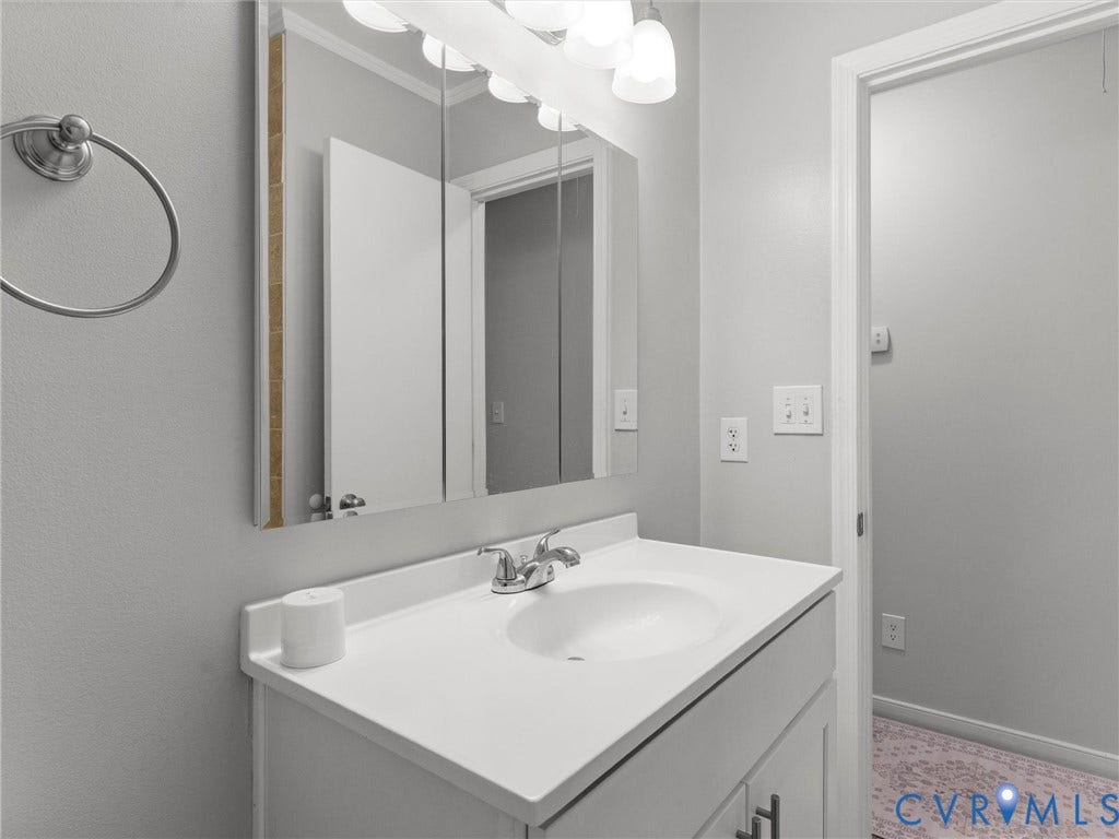 8708 Rainwater Road, Huntingcreek Hills, North Chesterfield, VA 23237 Vanity with an integrated sink and countertop, triple-panel mirrored medicine cabinet, and five-light vanity fixture