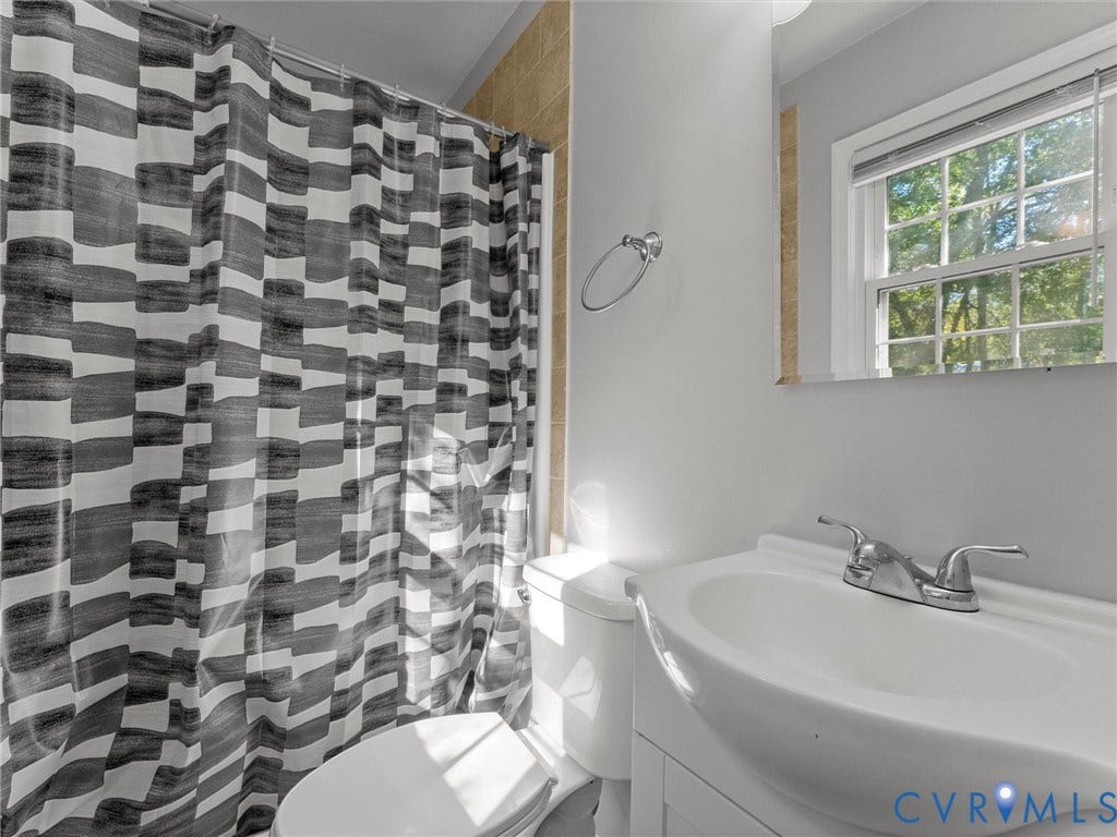 8708 Rainwater Road, Huntingcreek Hills, North Chesterfield, VA 23237 Bathroom featuring a white vanity cabinet, ceramic sink with a dual-handle faucet, wall-mounted mirror, and tile surround in the shower area