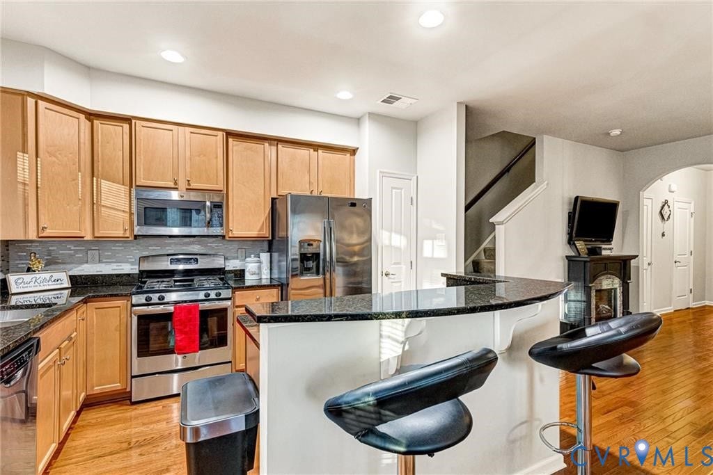 11600 Vicars Ridge Lane, Henrico, VA 23059 Kitchen with tasteful backsplash, a breakfast bar area, appliances with stainless steel finishes, light wood-style floors, and arched walkways