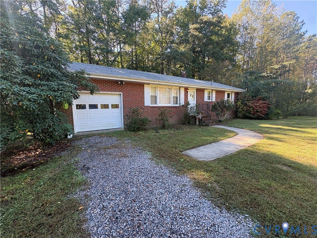 Single-story brick exterior featuring an attached one-car garage, white shutter accents, a stone gravel driveway, and a paved walkway