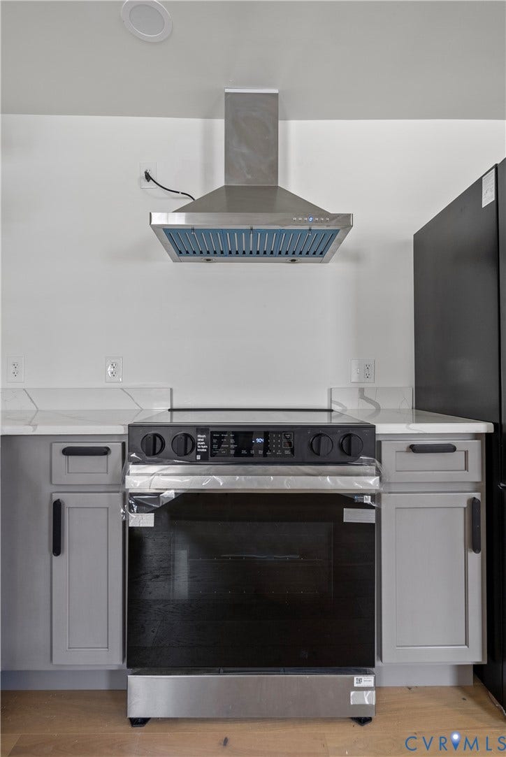 1708 Decatur Street, Swansboro, Richmond, VA 23224 Stainless steel chimney-style range hood, electric slide-in range, stone-composite countertop with matching backsplash, and grey shaker-style cabinetry with matte black hardware