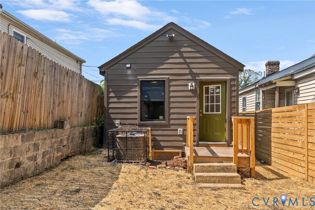 1708 Decatur Street, Swansboro, Richmond, VA 23224 Exterior elevation featuring horizontal siding, a rear wood deck with concrete steps, and a fenced backyard with a stone retaining wall