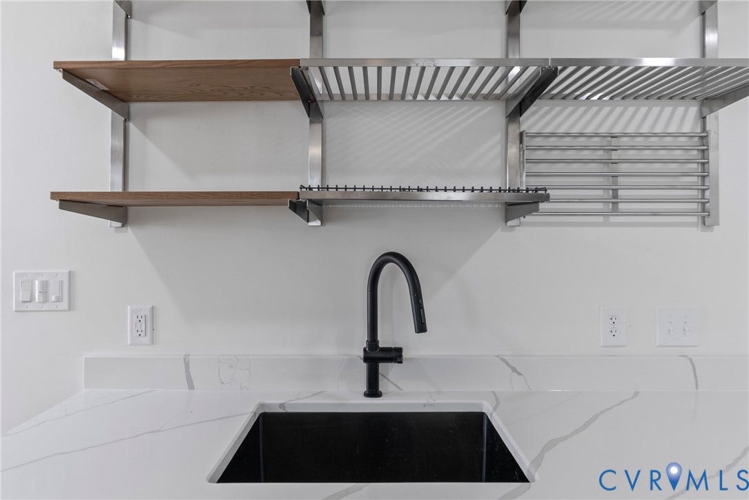 1708 Decatur Street, Swansboro, Richmond, VA 23224 Undermount sink with a matte black gooseneck faucet, white stone-patterned countertop with matching backsplash, and industrial-style shelving featuring metal racking and wood-finish accents