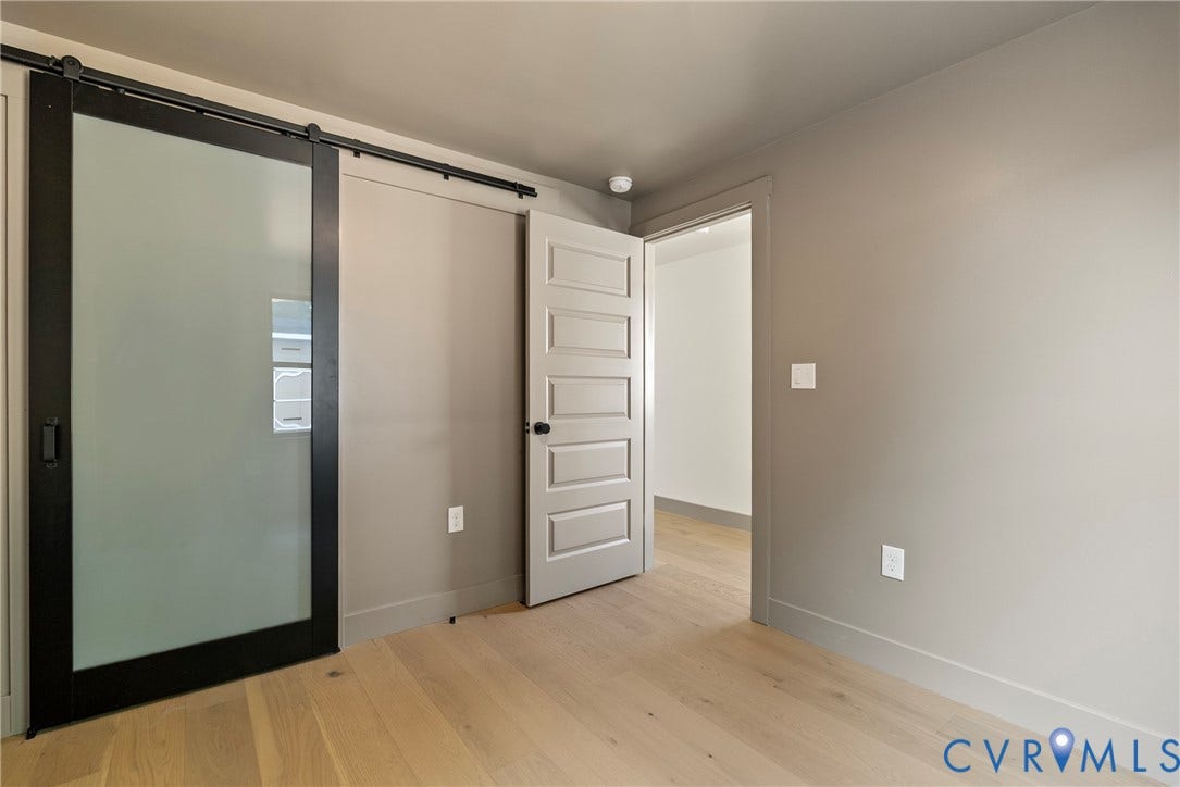 1708 Decatur Street, Swansboro, Richmond, VA 23224 Sliding door with a black frame and frosted glass panel, five-panel interior door with matte black hardware, and wood-finish flooring
