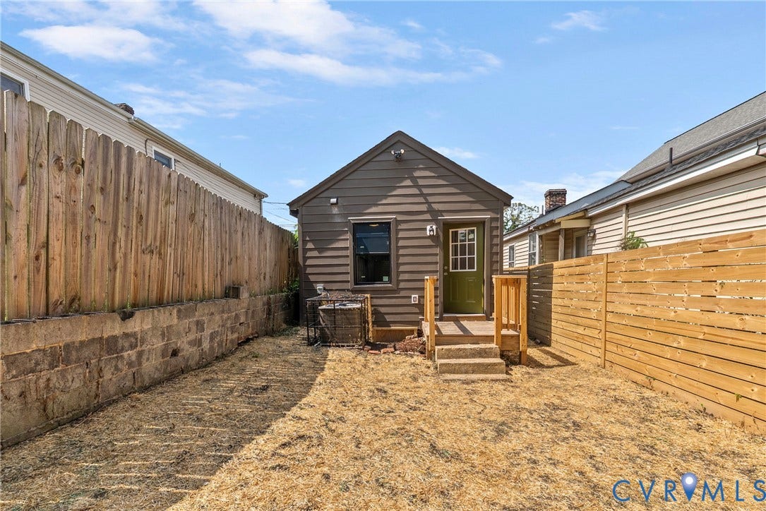 1708 Decatur Street, Swansboro, Richmond, VA 23224 Rear exterior featuring horizontal siding, a wooden staircase, a solid-paneled door with glass upper light, a stone retaining wall, and wood privacy fencing