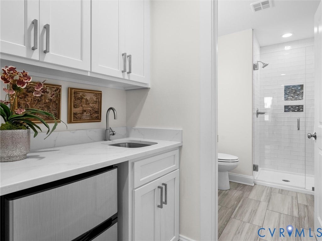 1412 Ascot Hill Terrace, Midlothian, VA 23112 White shaker-style cabinetry with satin nickel hardware, stone-composite countertop, stainless steel undermount sink, and tiled walk-in shower featuring a mosaic-tile recessed niche