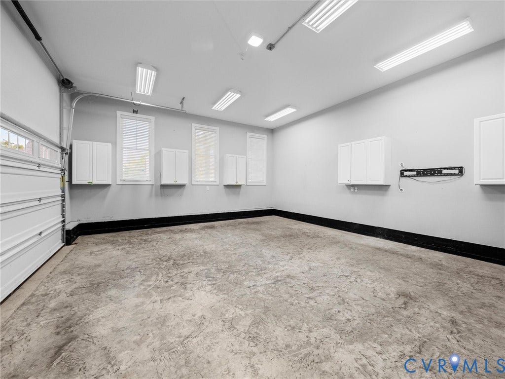 1412 Ascot Hill Terrace, Midlothian, VA 23112 Spacious garage featuring a concrete floor, built-in white cabinetry, multiple windows, and overhead fluorescent lighting