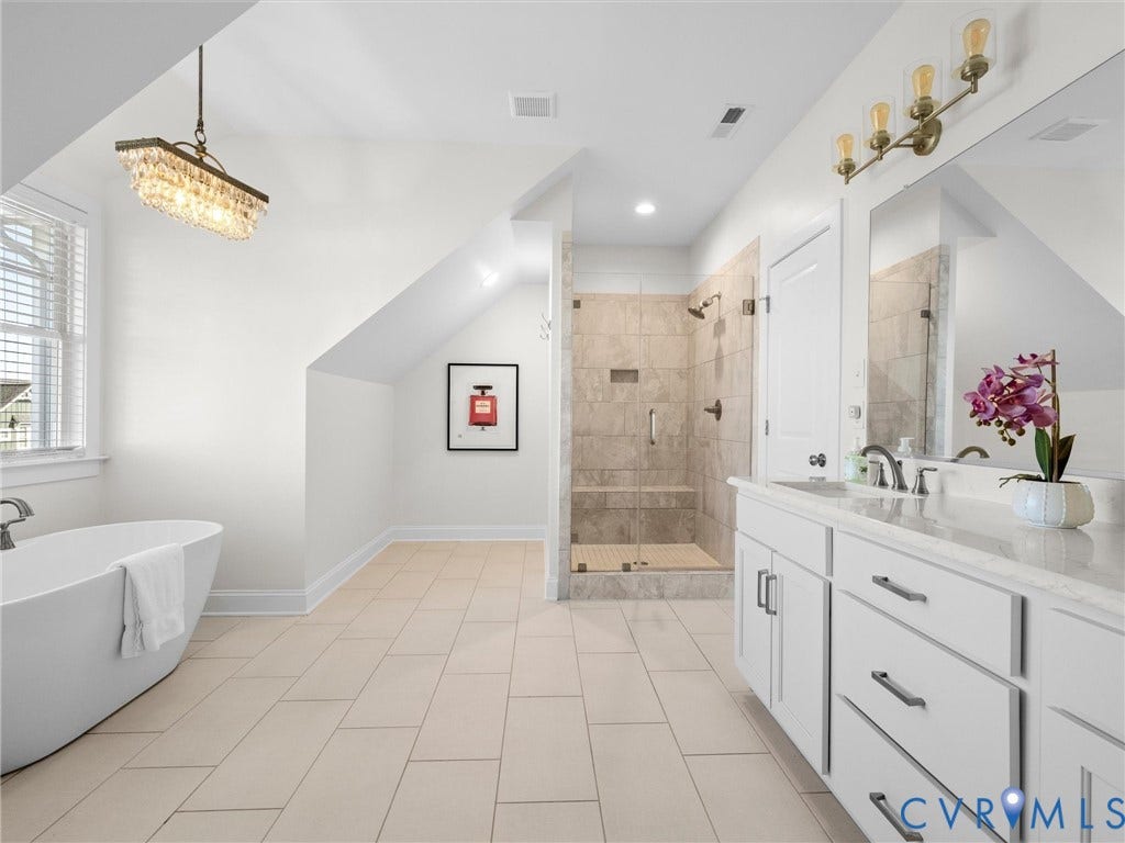 1412 Ascot Hill Terrace, Midlothian, VA 23112 Freestanding soaking tub, walk-in shower with tile surround and built-in bench, dual-sink vanity with light-colored stone countertop, and glass-front lighting fixtures