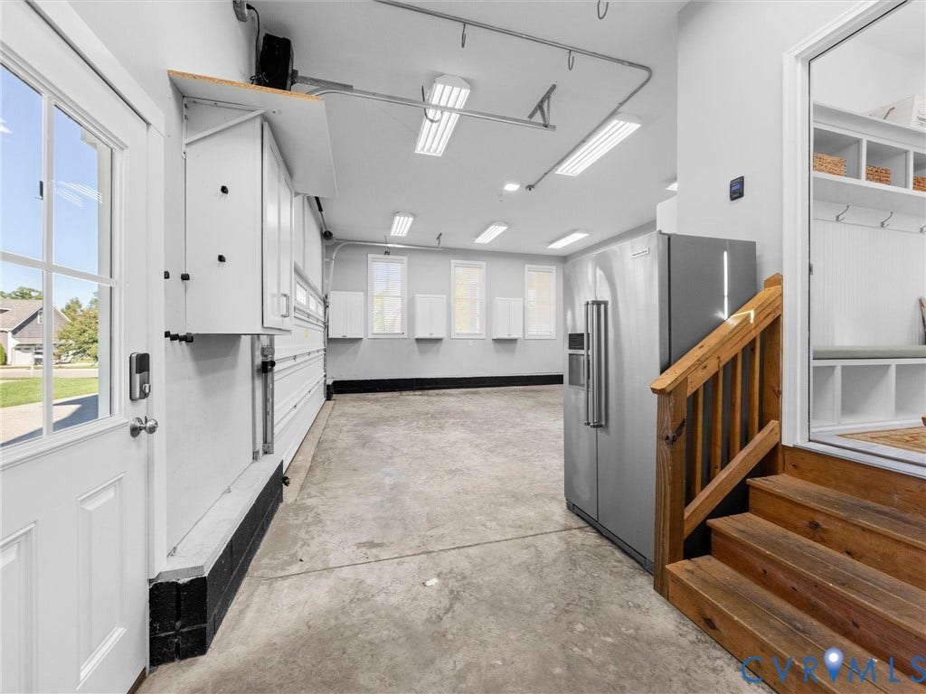 1412 Ascot Hill Terrace, Midlothian, VA 23112 Garage space featuring white wall-mounted storage cabinetry, overhead fluorescent lighting, a stainless steel refrigerator, and wooden staircase leading to the interior
