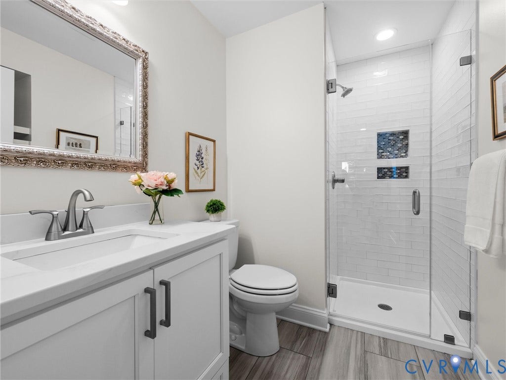 1412 Ascot Hill Terrace, Midlothian, VA 23112 White vanity with stone countertop and metal hardware, subway tile shower enclosure with integrated shelving, glass shower door, and wood-finish flooring