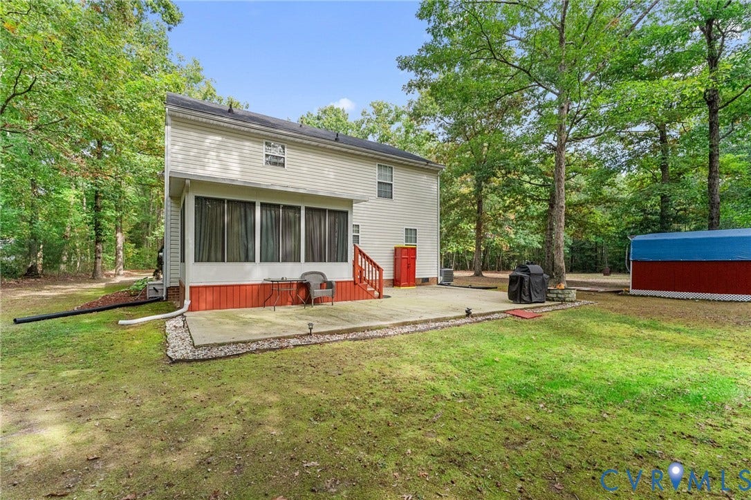 17030 Courtney Road, Reedy Church District, Hanover, VA 23069 Rear exterior featuring a concrete patio, a screened-in porch with wood-finish siding, and a detached storage structure set against a wooded landscape