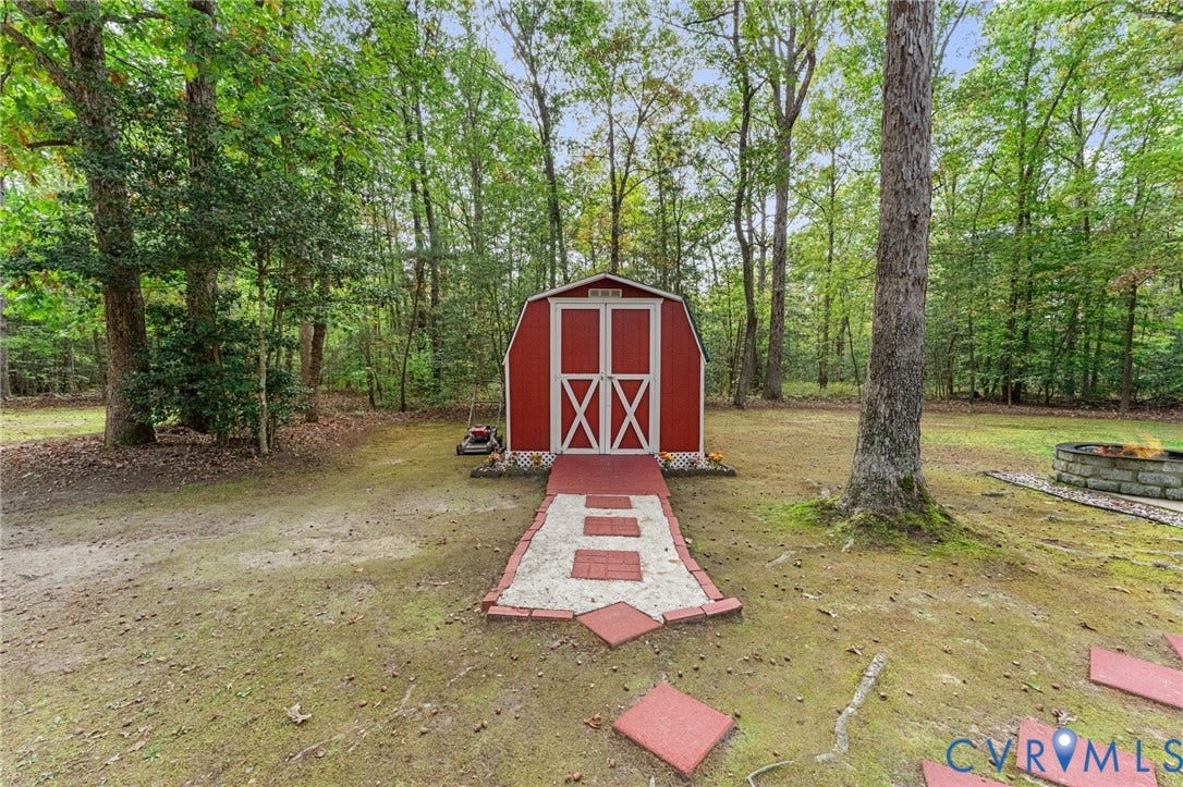 17030 Courtney Road, Reedy Church District, Hanover, VA 23069 Storage structure featuring a gambrel roof, red-painted exterior with white trim, double-door entry, gravel and paver pathway, and a stone-built fire pit
