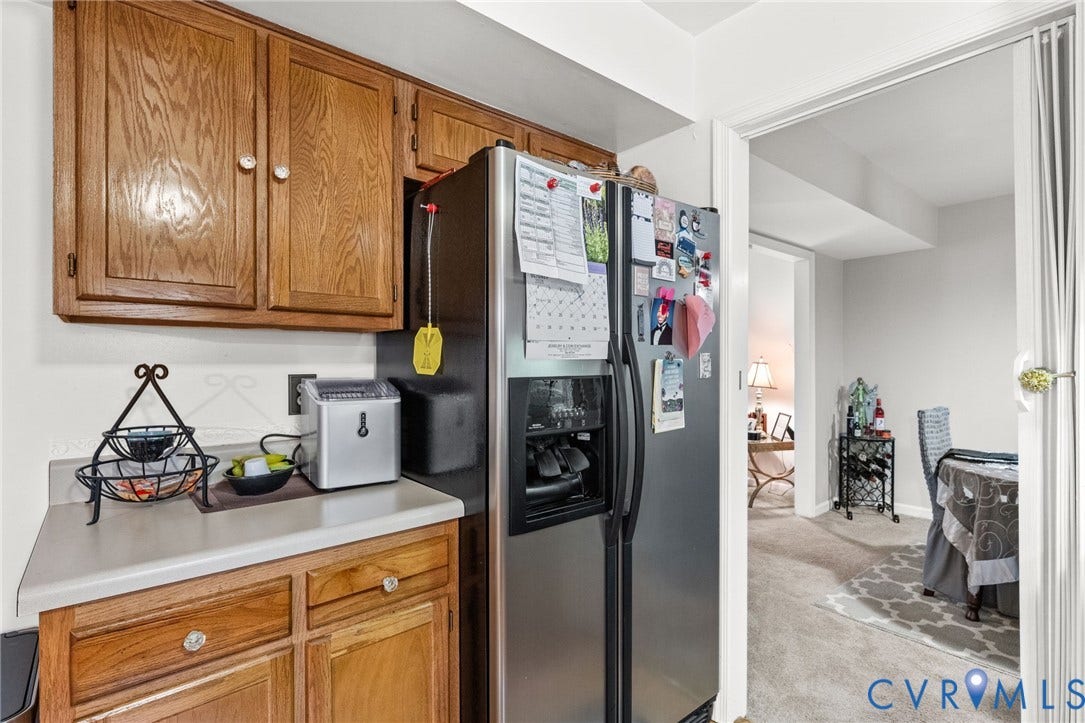 17030 Courtney Road, Reedy Church District, Hanover, VA 23069 Kitchen cabinetry featuring wood-finish grain, solid surface countertop, and stainless steel refrigerator