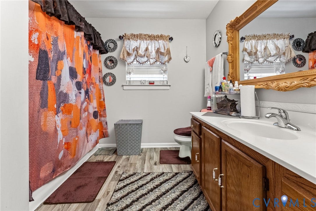 17030 Courtney Road, Reedy Church District, Hanover, VA 23069 Bathroom featuring a single-sink vanity with wood-finish cabinetry, an integrated white countertop, wood-finish flooring, and a window