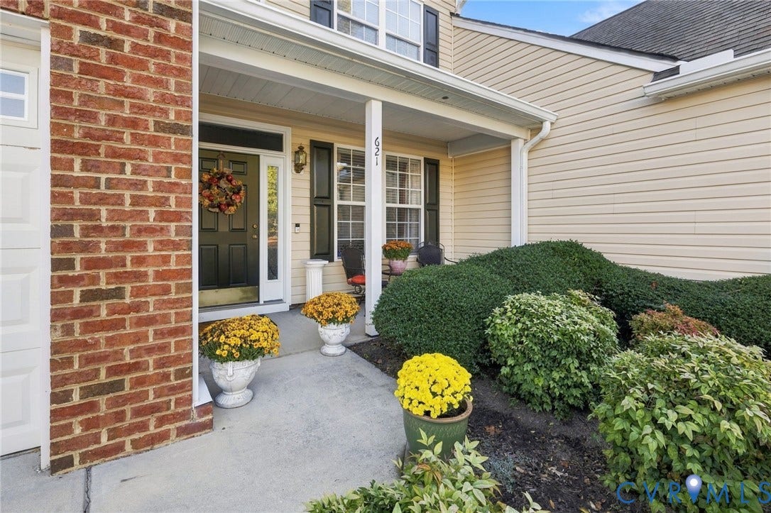 621 Scotter Hills Court, Midlothian, VA 23114 Covered front entryway featuring a brick facade, vinyl siding, shutter-accented windows, and a concrete walkway