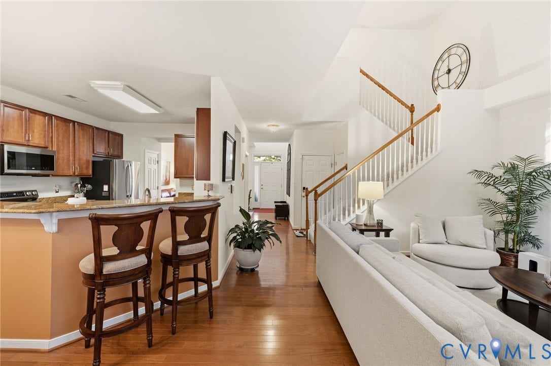 621 Scotter Hills Court, Midlothian, VA 23114 Open-concept floor plan featuring wood-finish flooring, a kitchen breakfast bar with stone-surfaced countertops, custom wood cabinetry, and a staircase with a wooden banister