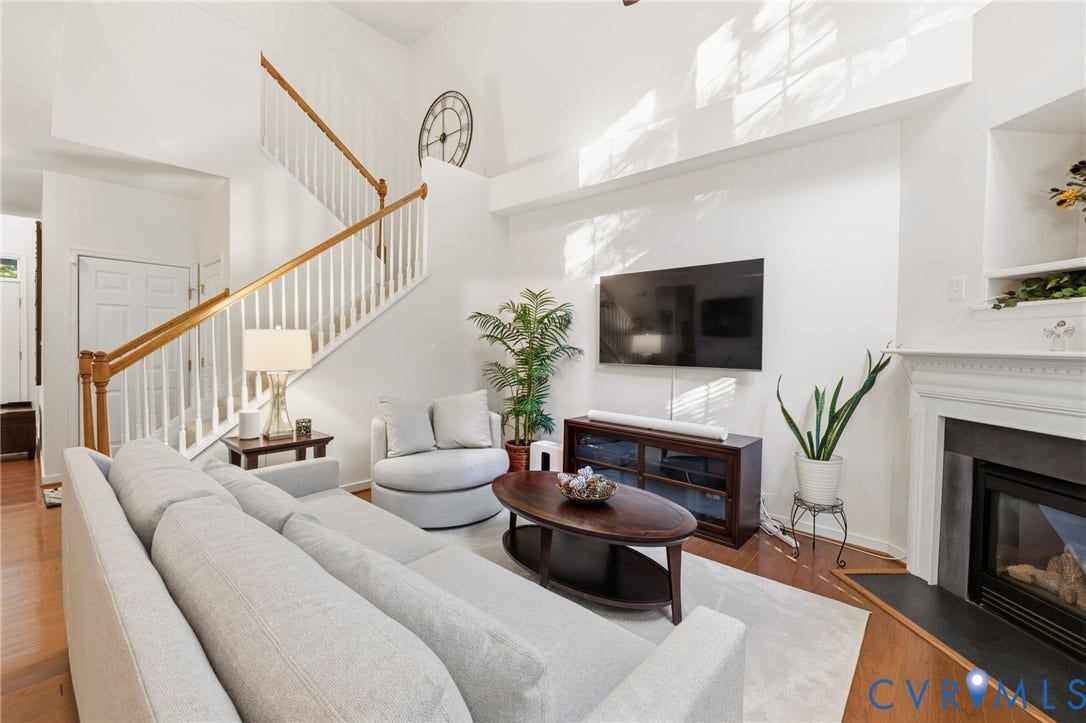 621 Scotter Hills Court, Midlothian, VA 23114 Living area featuring vaulted ceilings, a fireplace with a mantel and stone-finish surround, wood-finish flooring, and a staircase with a wooden handrail and balusters