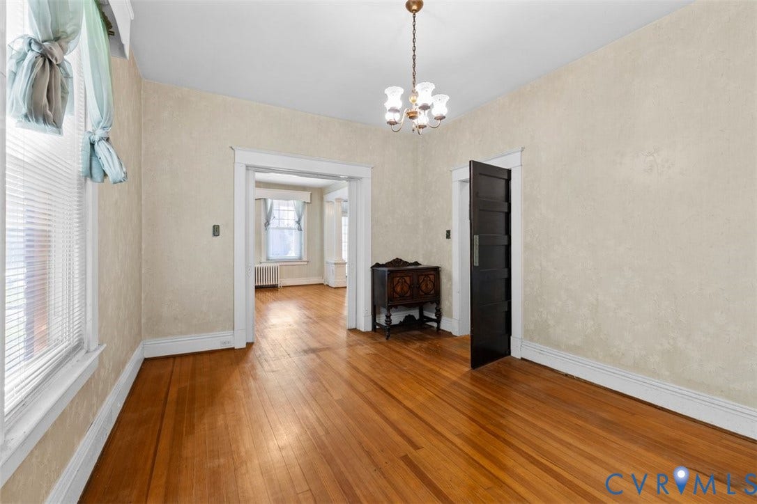 210 W Graham Road, Richmond, VA 23222 Interior room featuring wood-finish flooring, textured wall finishes, a five-panel solid wood door, and a multi-arm metal chandelier