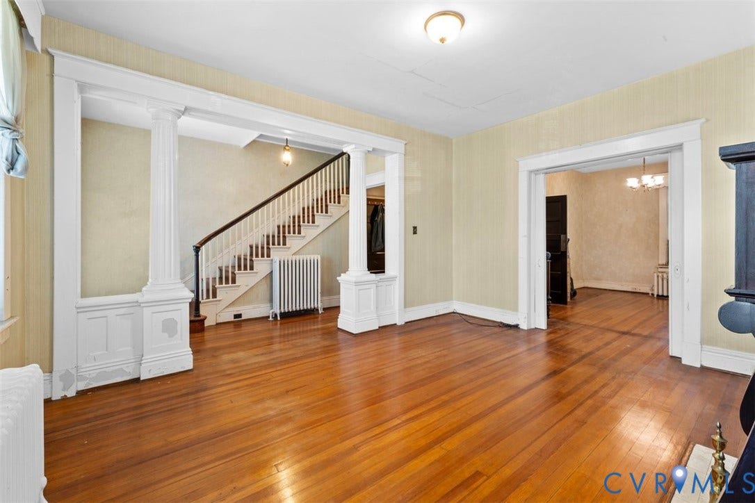 210 W Graham Road, Richmond, VA 23222 Interior space featuring wood-finish flooring, architectural columns with wainscoting detail, a staircase with a wooden handrail, and prominent millwork trim throughout the entries