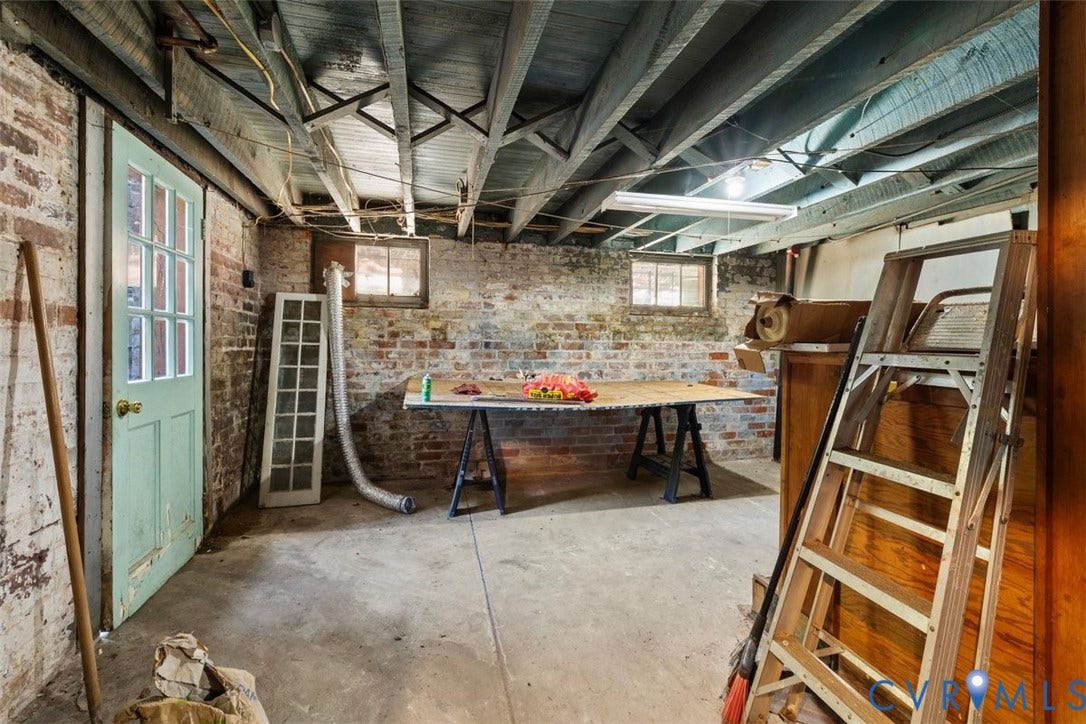 210 W Graham Road, Richmond, VA 23222 Lower-level space featuring exposed wood joist ceilings, painted brick masonry walls, concrete flooring, and an exterior-access door with glass lites