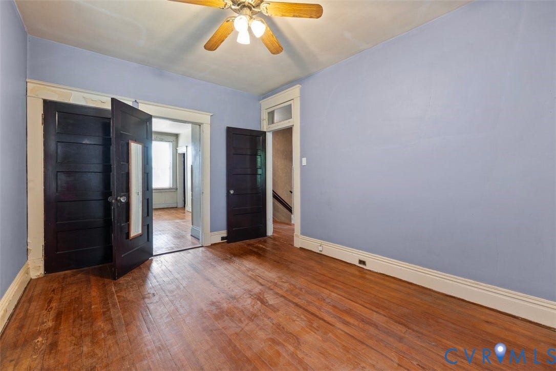 210 W Graham Road, Richmond, VA 23222 2nd bedroom with wood-finish flooring, dark-stained five-panel doors, tall white casing trim, and a ceiling-mounted light fixture