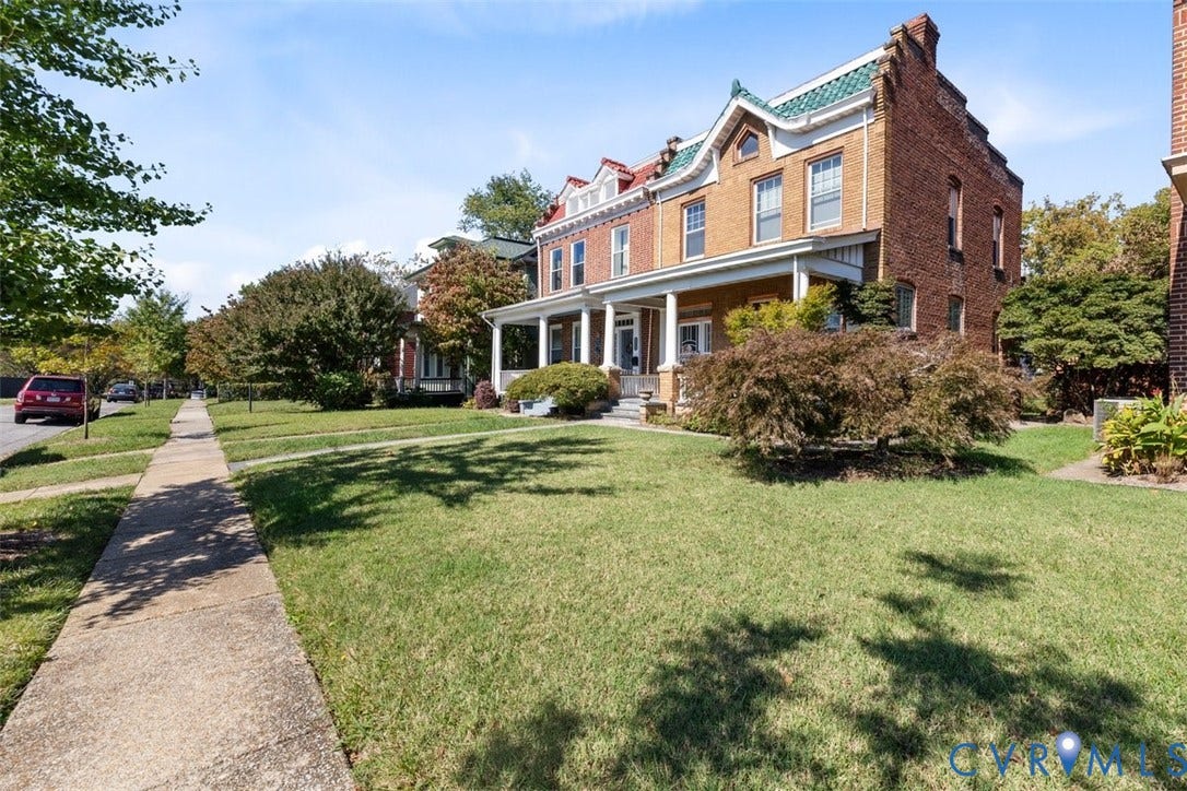210 W Graham Road, Richmond, VA 23222 Traditional brick exterior featuring a covered front porch, dual dormer windows, green shingle roof accents, and mature landscaping