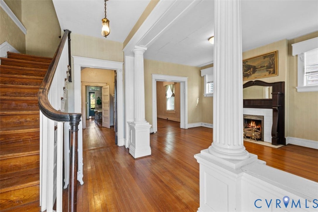 210 W Graham Road, Richmond, VA 23222 Interior entry featuring wood-finish flooring, classic fluted columns, a wood staircase with a curved banister, and a fireplace with a built-in mantel