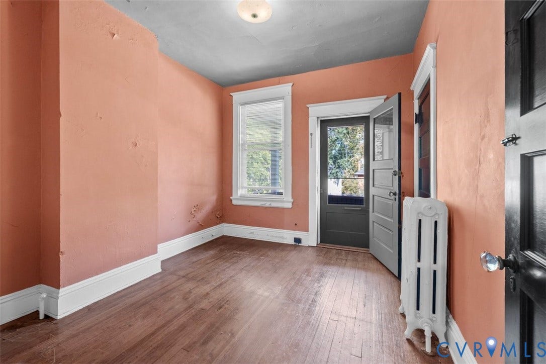 210 W Graham Road, Richmond, VA 23222 Third bedroom featuring wood-finish flooring, a white cast-iron radiator, a single-pane window with white trim, and a black-finished door with an integrated window pane