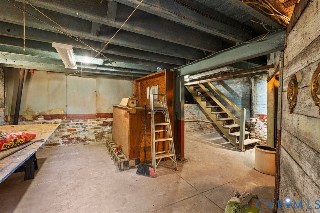 210 W Graham Road, Richmond, VA 23222 Unfinished lower level featuring exposed joist ceilings, concrete flooring, painted masonry walls, and wooden staircase