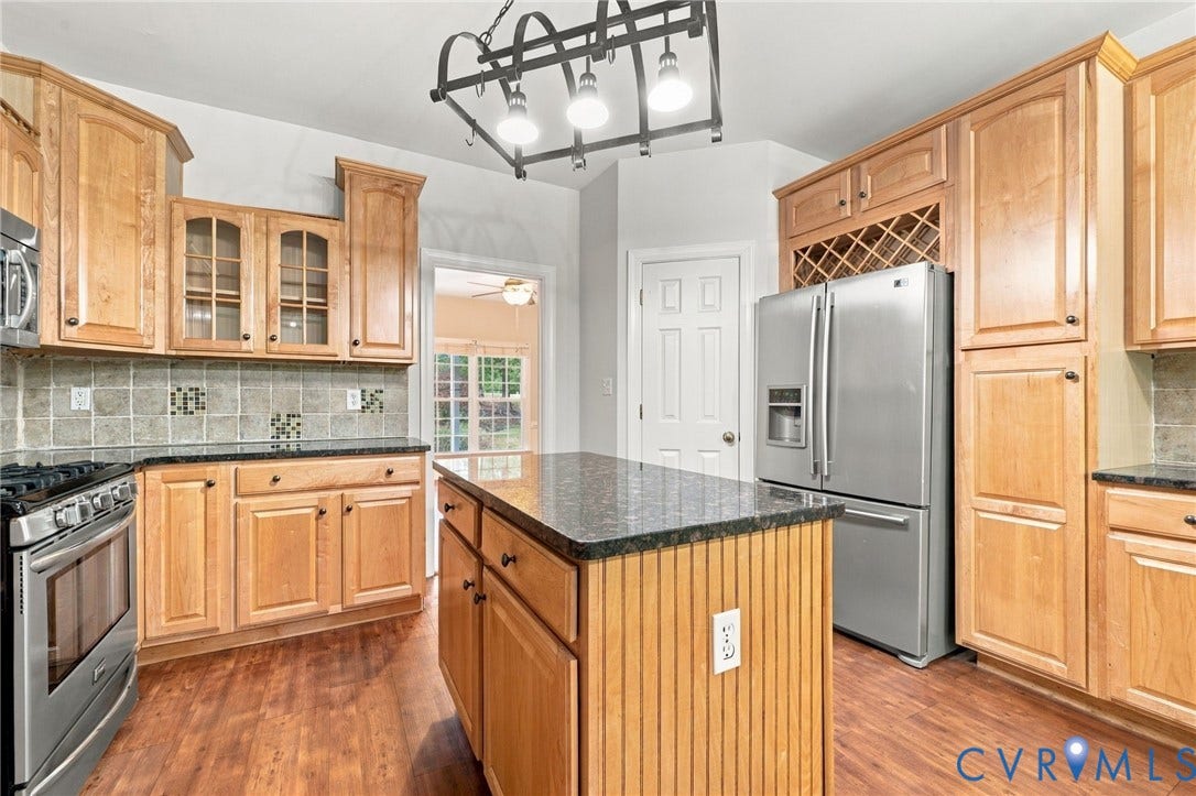 2654 Academy Road, Powhatan, VA 23139 Kitchen featuring wood cabinetry, a central island with beadboard detailing, granite countertops, and stainless-steel appliances