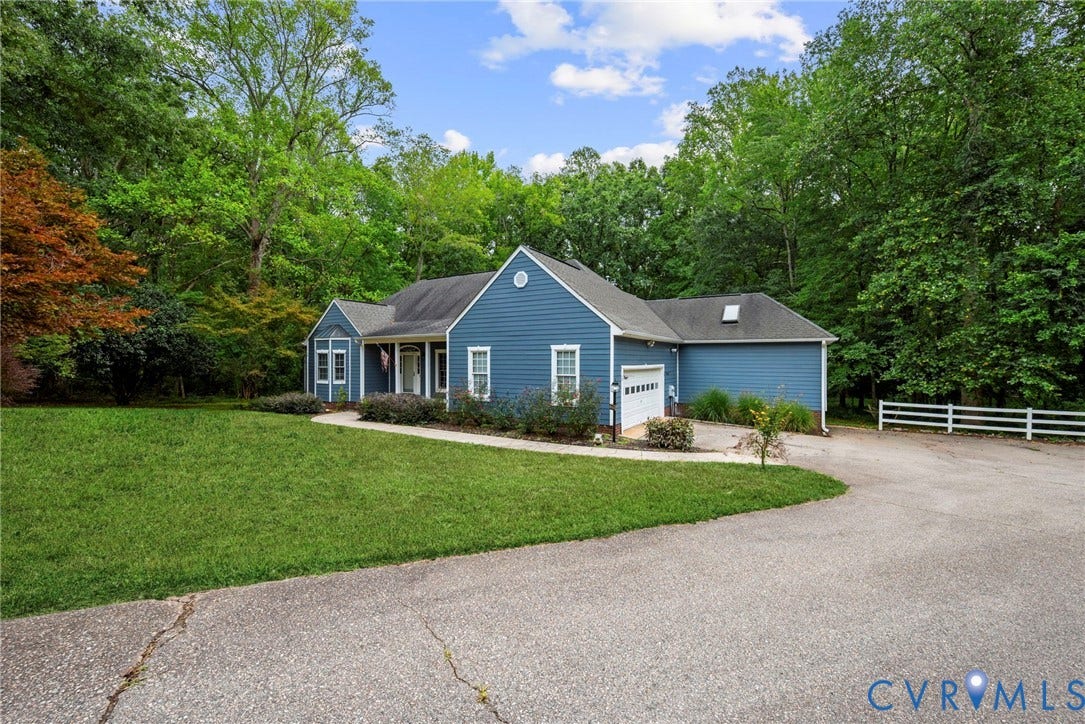 2654 Academy Road, Powhatan, VA 23139 Blue-sided exterior featuring an asphalt shingle roof, attached garage, manicured lawn, and white rail fencing at the end of the driveway. Virtually edited grass