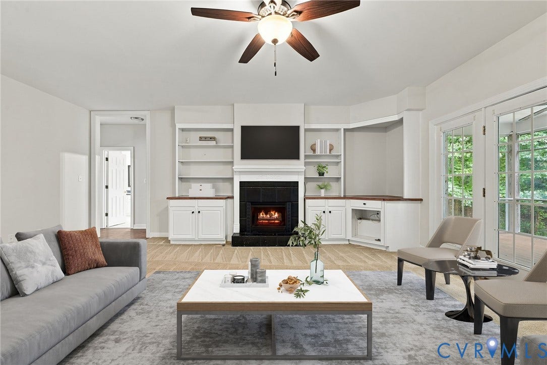 2654 Academy Road, Powhatan, VA 23139 Living space featuring a central fireplace with black brick, integrated white built-in shelving, a ceiling fan with integrated lighting, and glass-paneled double doors. Virtually staged concept